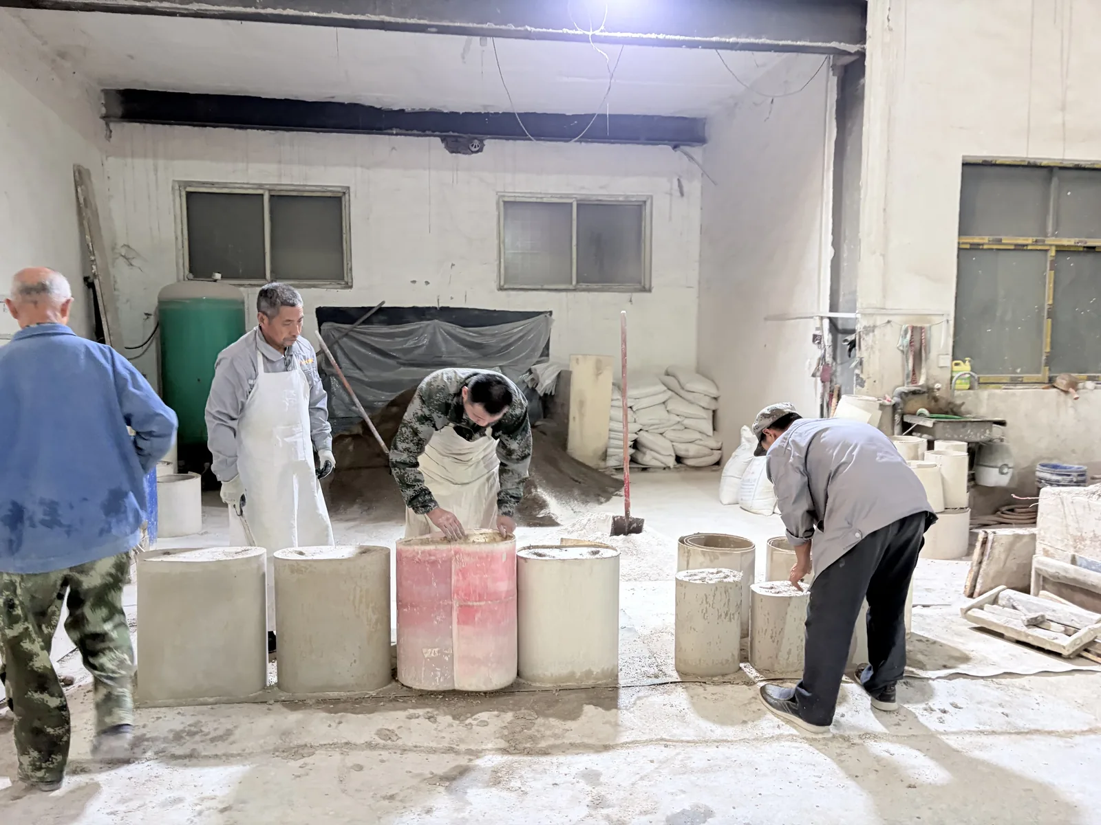 Workers preparing mold materials in a bronze workshop