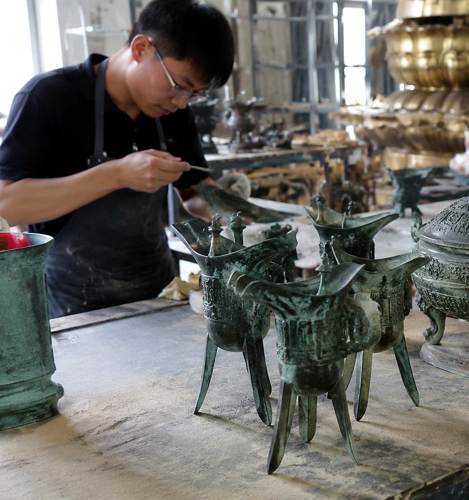Luoyang workshop scene with bronze reproduction objects on a sourcing table